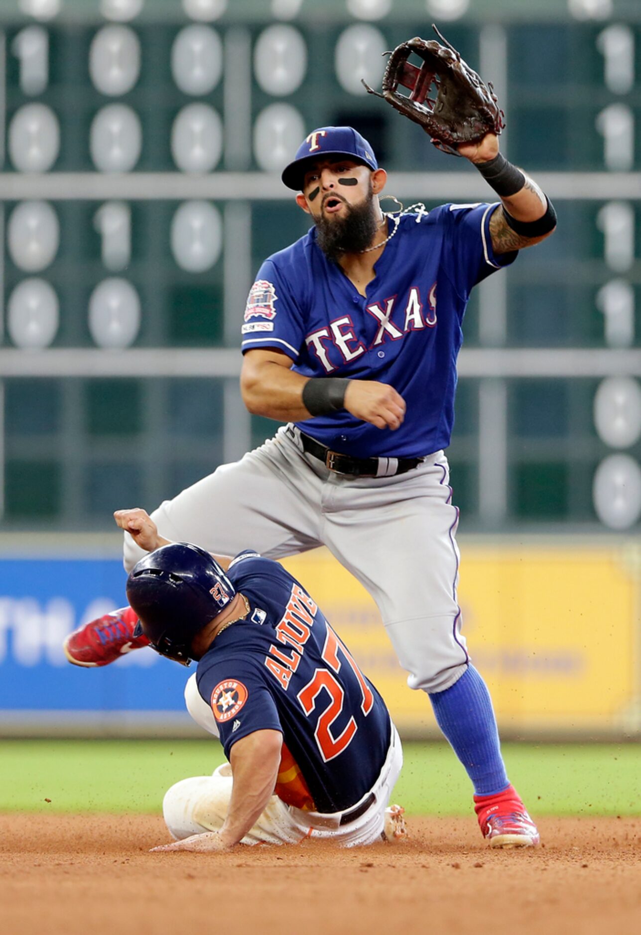 Texas Rangers second baseman Rougned Odor, top, jumps to avoid a slide by Houston Astros...