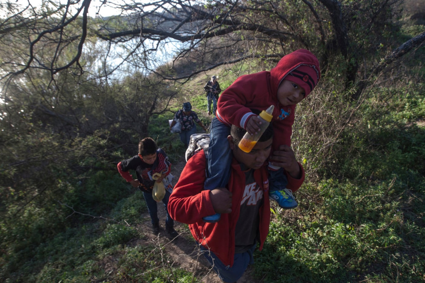 Border crossers walk along the Mexican side of the border dividing the cities of Eagle Pass...