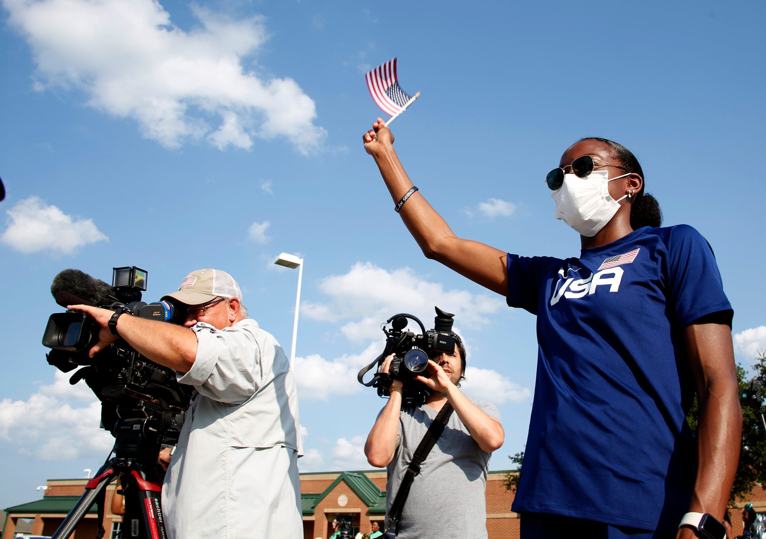 Mansfield track star Jasmine Moore waves an American flag as she greets a caravan of...