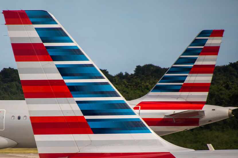 An American Airlines plane taxis away from another parked at the gates of Las AmÅ½ricas...