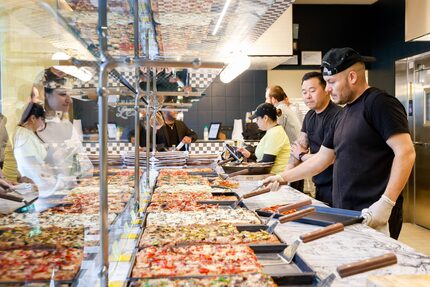 Mario Rios (right) serves a slice of pizza at Pizza Leila in Dallas on Monday, March 20,...