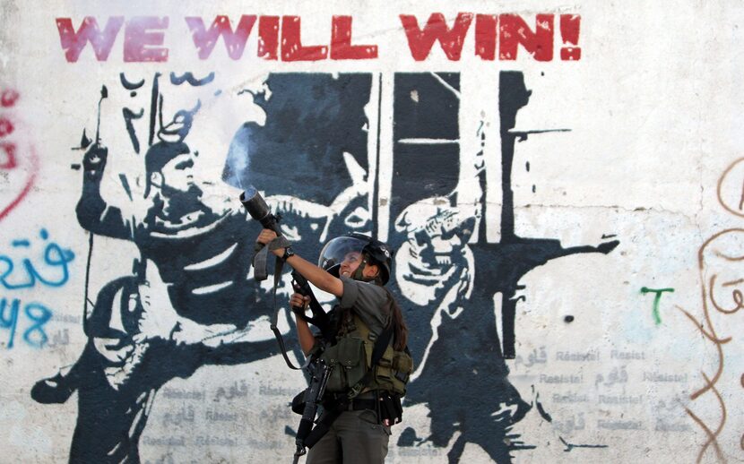  A female Israeli border guard fires tear gas towards Palestinian demonstrators (unseen)...