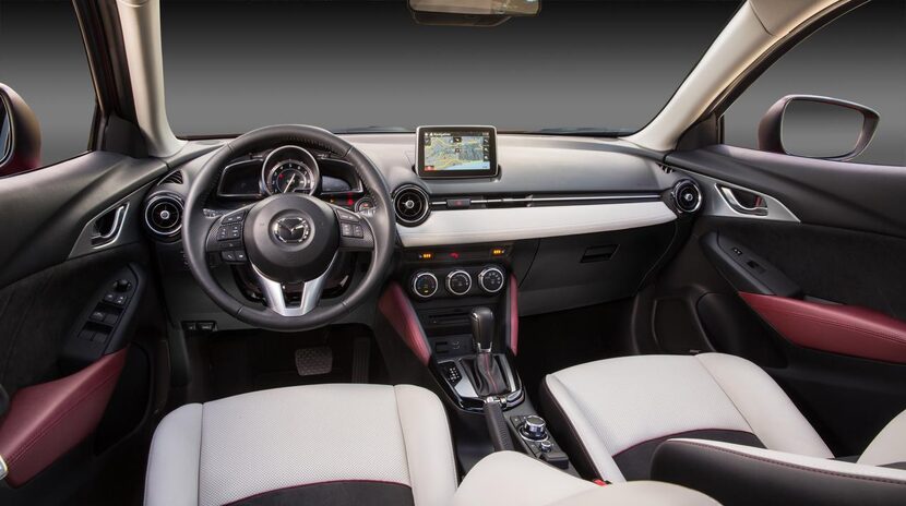 Inside the 2016 Mazda CX-3,  the dashboard wraps sleekly around the base of the windshield,...