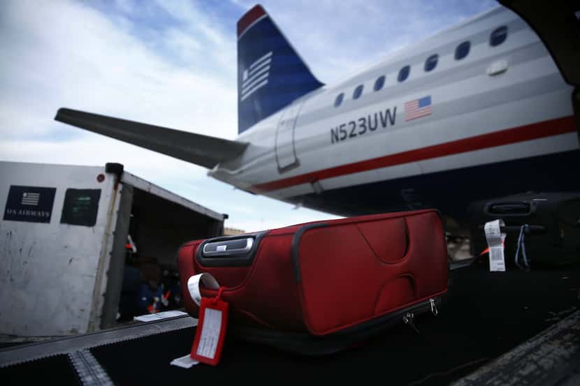 US Airways baggage is unloaded on the ramp at Sky Harbor International Airport in Phoenix,...