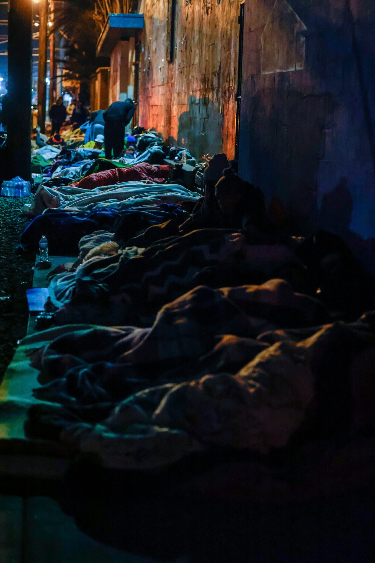 Migrants spend the night on the street at the Centro Pastoral Sagrado Corazon in El Paso on...