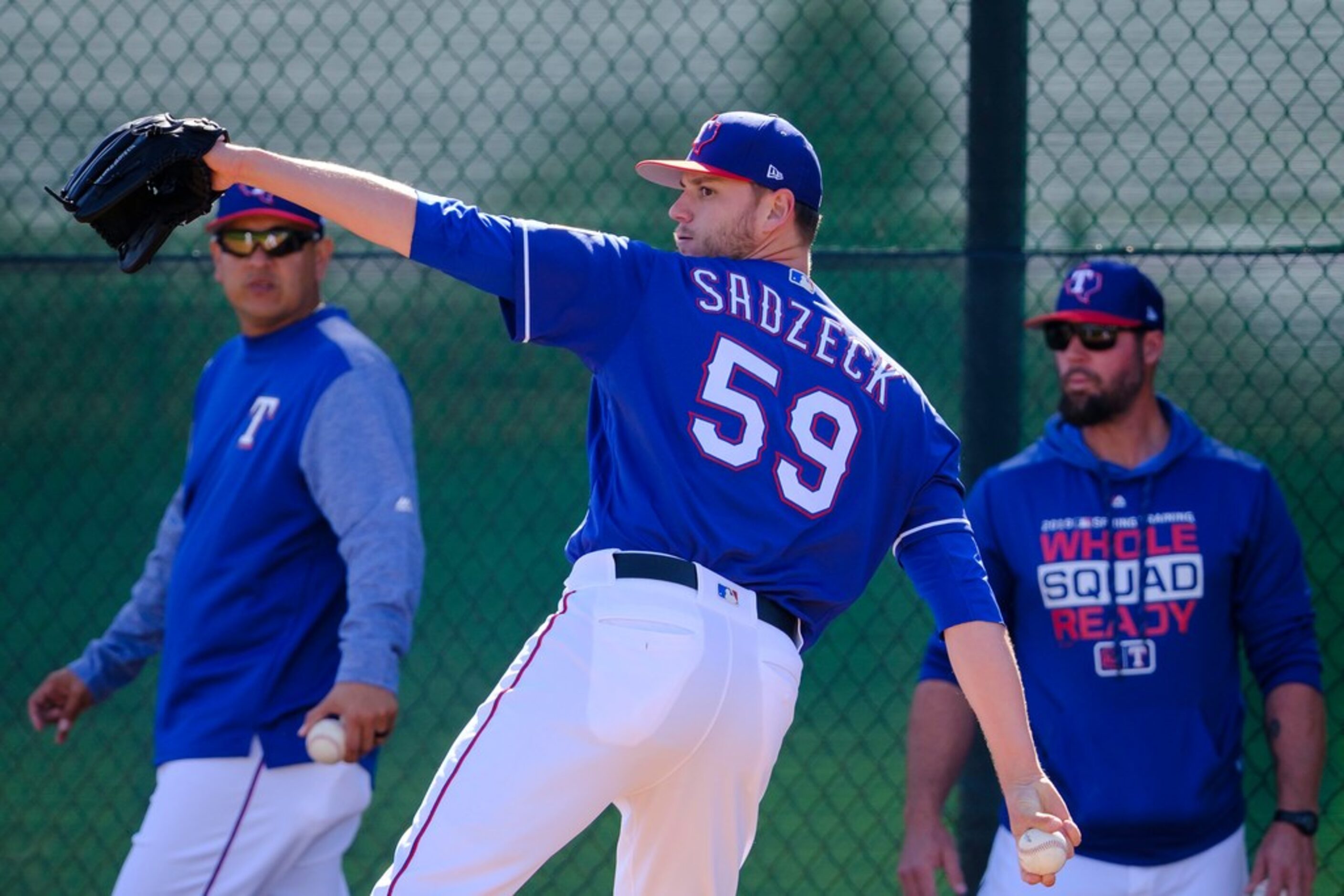 Texas Rangers pitcher Connor Sadzeck throws a bullpen session as pitching coach Julio Rangel...