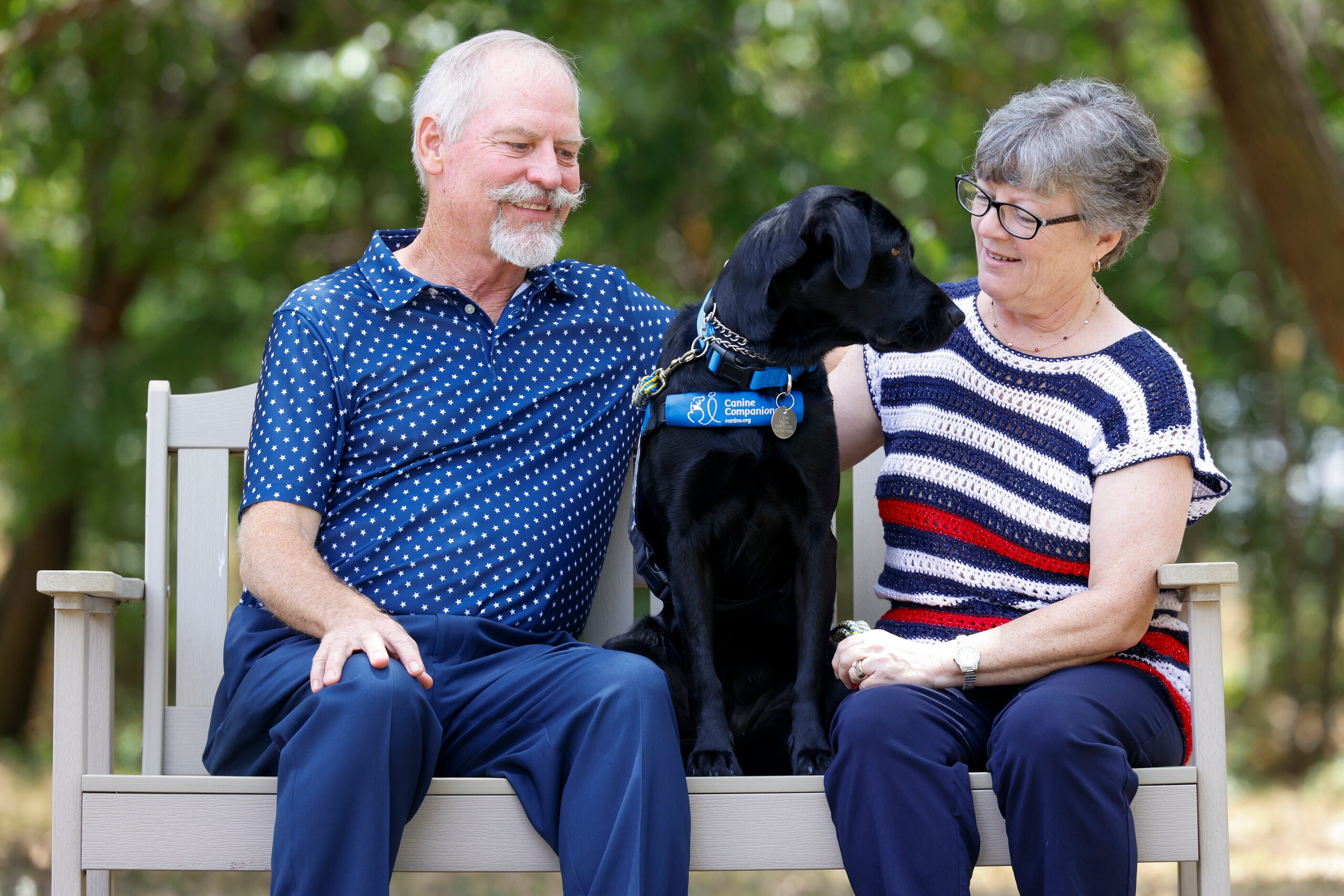 Veteran Kathy Schneider with her dog Dakota, and husband Ray share a moment in between a...