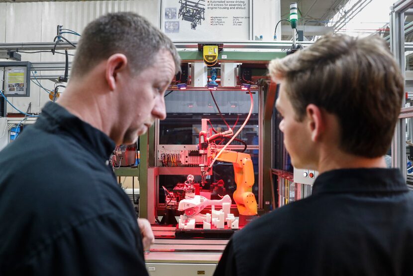  A.J. Scherman, 37, left, works with fellow apprentice Ryan Buzzy, 18, right, on a robotics...