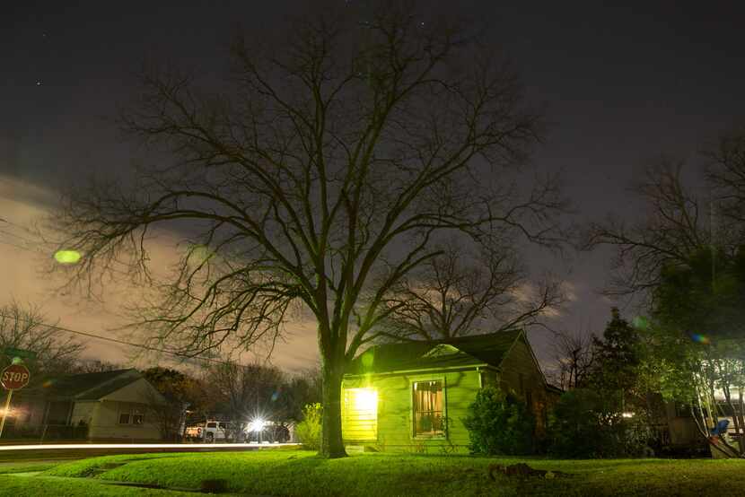 Street lights, a vehicle and a porch light illuminates Ivandell Avenue in the West Oak Cliff...