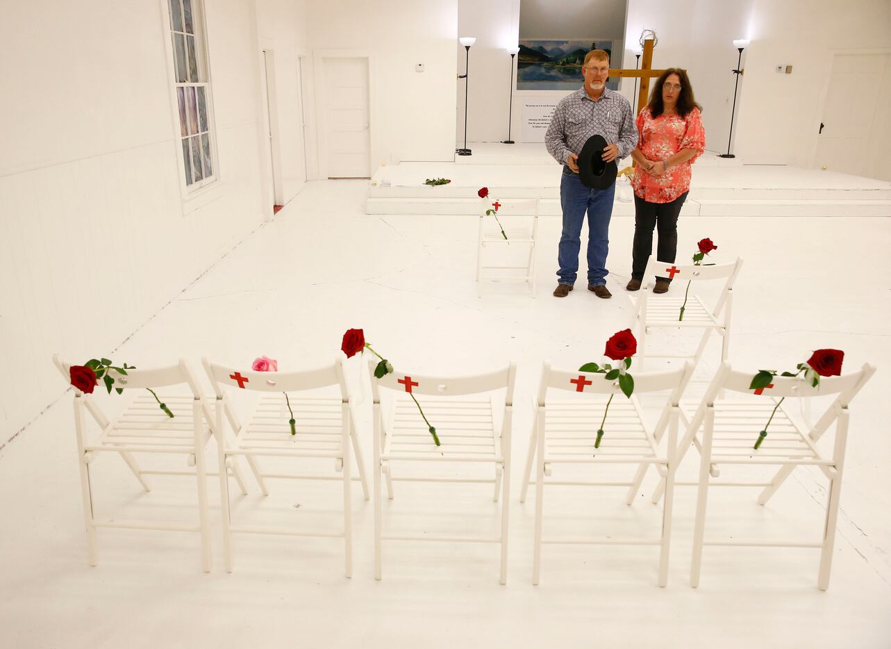 Robert Kunz and his wife Lisa Kunz look at chairs and roses representing the slain as...