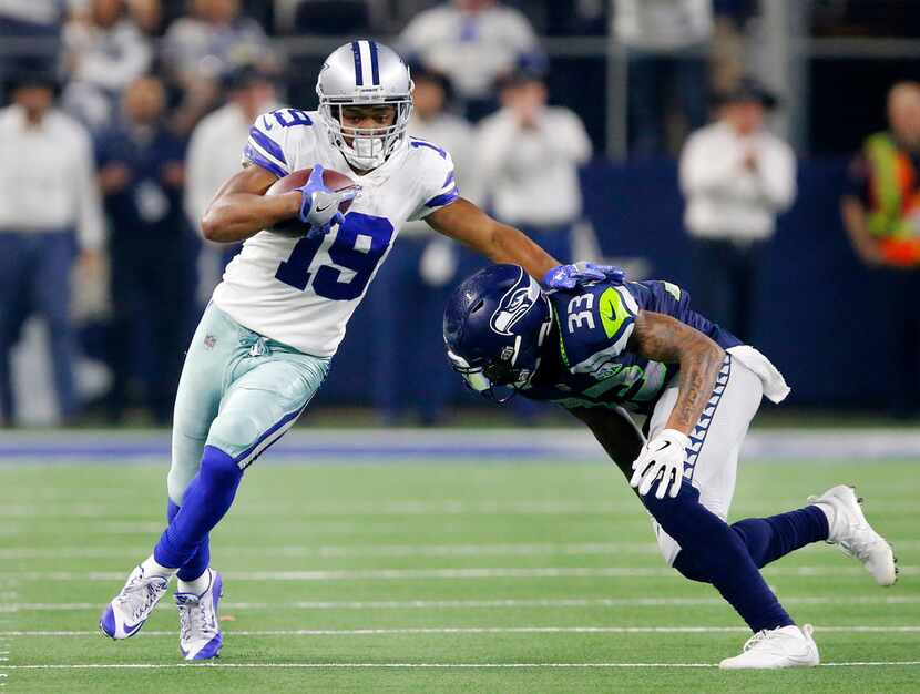 Cowboys wide receiver Amari Cooper (19) tries to avoid the tackle by Seattle Seahawks free...