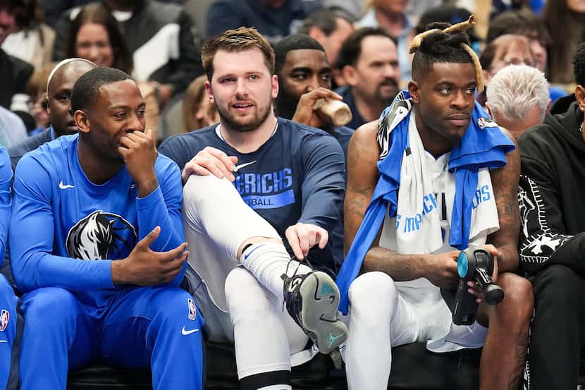 Dallas Mavericks guard Luka Doncic (center) watches from the bench during the first half of...