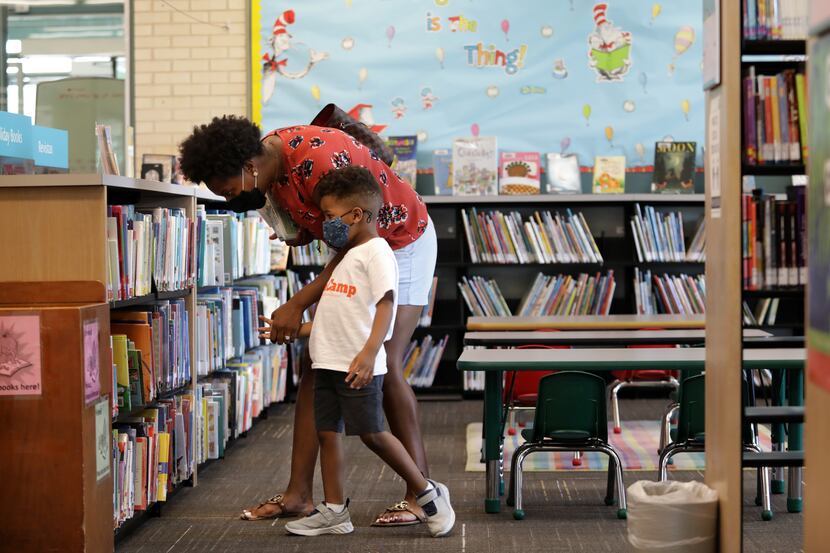 Whitney Lewis and 4-years-old Carter Lewis look through the available books at the North Oak...