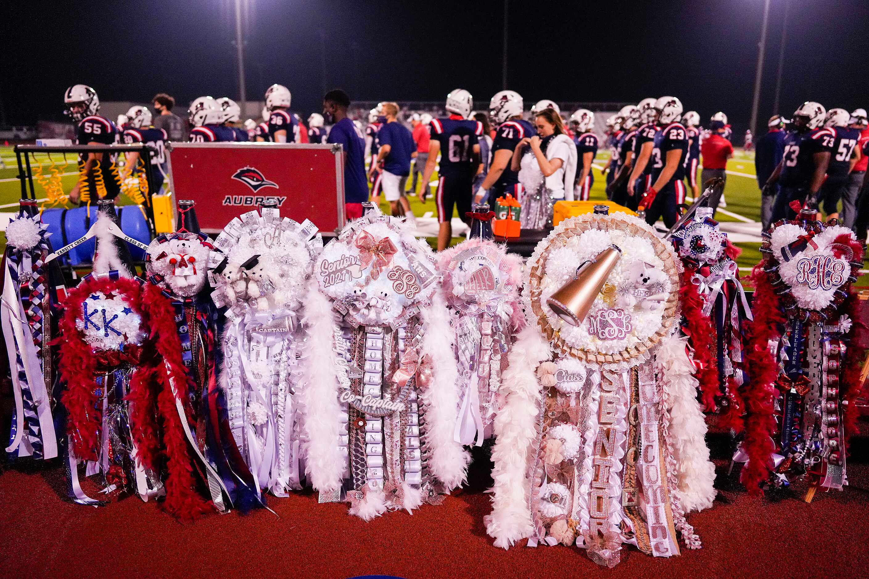 Homecoming mums line the sidelines behind the Aubrey bench during the second half of a high...