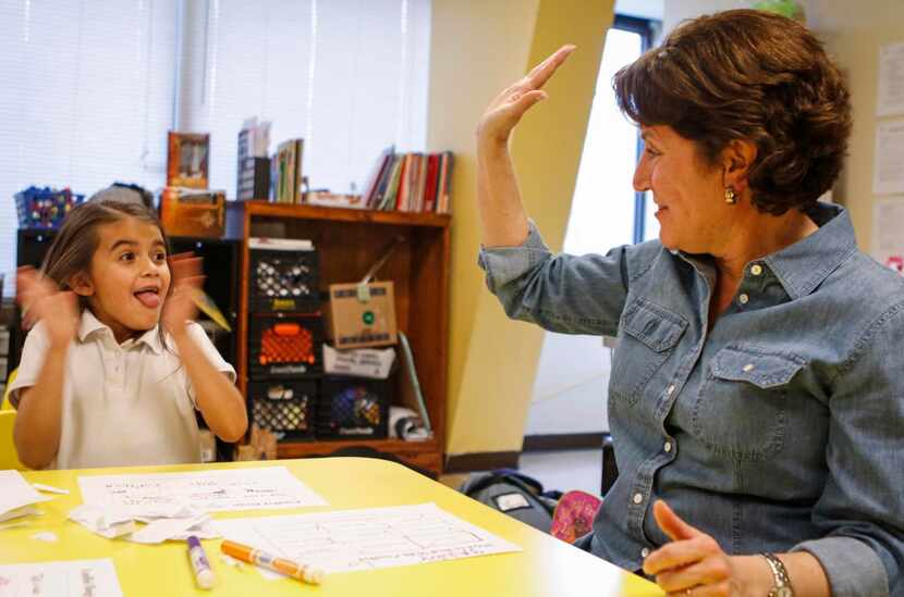 
Volunteer Susan Riffe (right) offers Gabby Lopez, 7, a high-five after she wins “conflict...