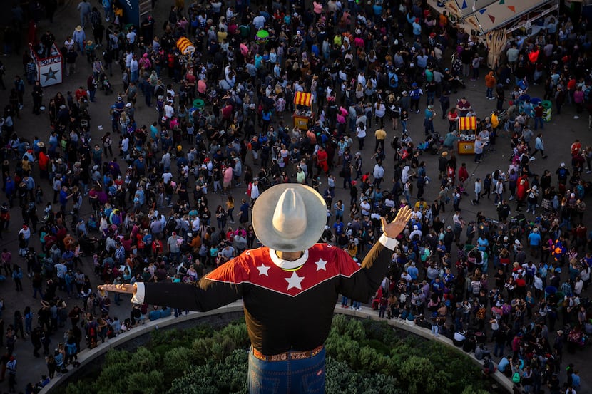 The last rays of sunlight fall over Big Tex as crowds rill the State Fair of Texas in Fair...