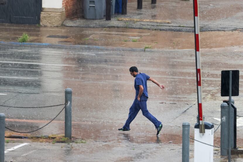 A man leaps as he moves through the rain along Commerce Street in downtown Dallas on Wednesday.