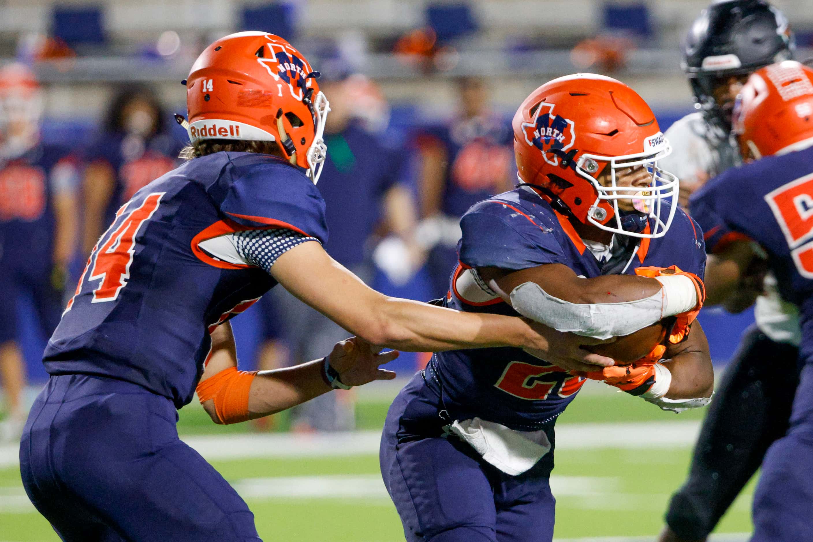 McKinney North quarterback Colin Hitchcock (14) hands off to running back Jadan Smith during...