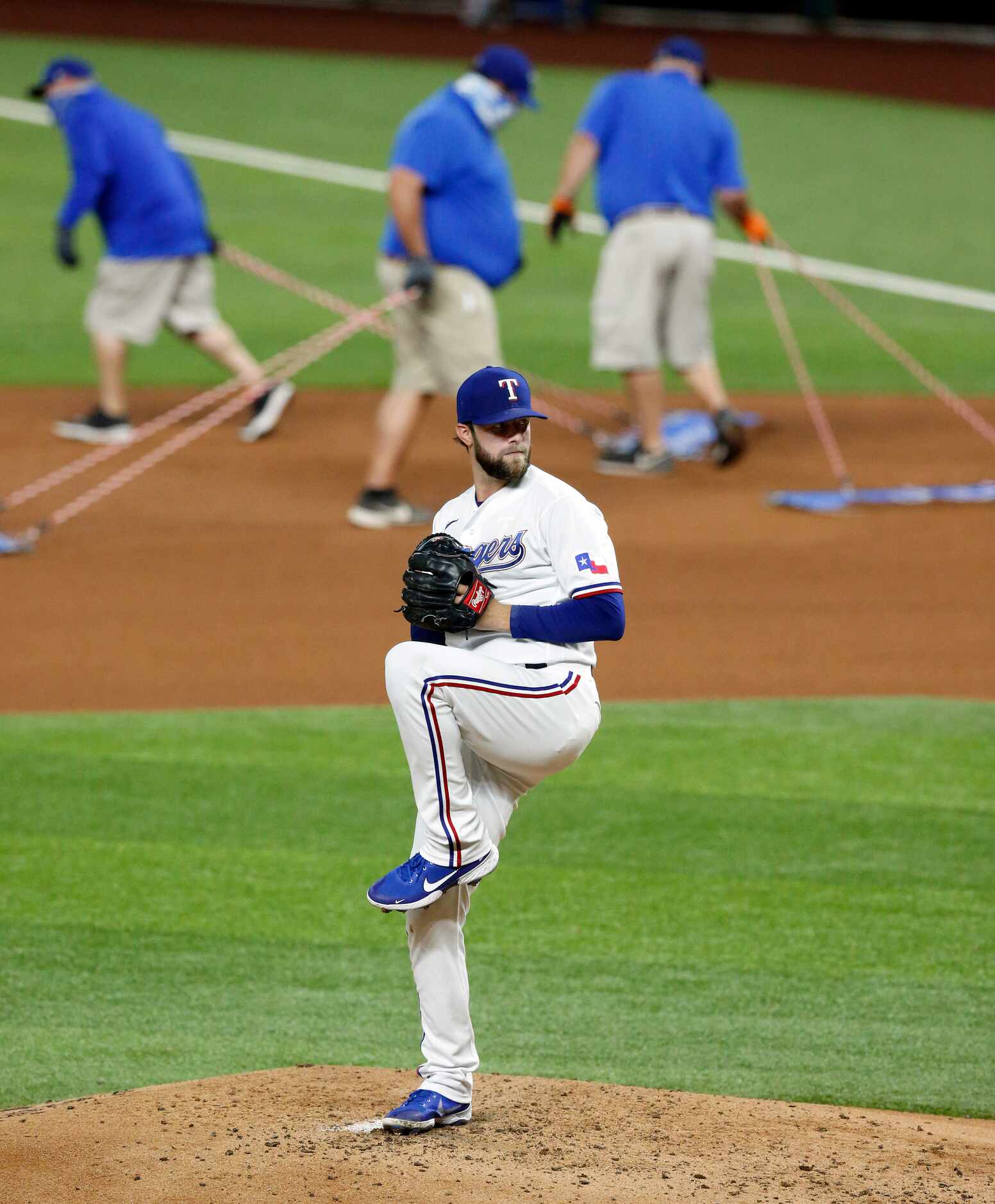 Texas Rangers starting pitcher Jordan Lyles (24) warms up as the grounds crew rakes the...