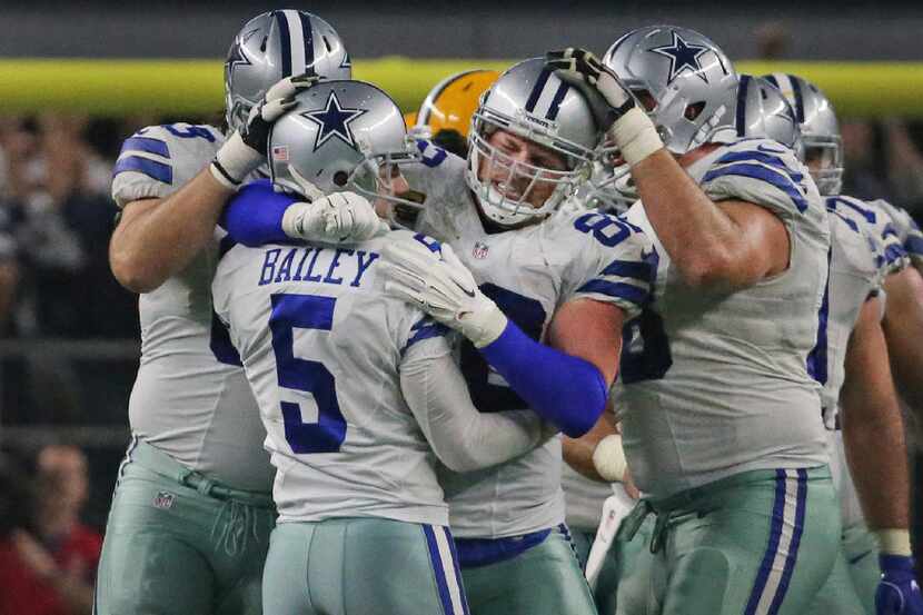Dallas Cowboys tight end Jason Witten (82) and other teammates hug kicker Dan Bailey (5)...