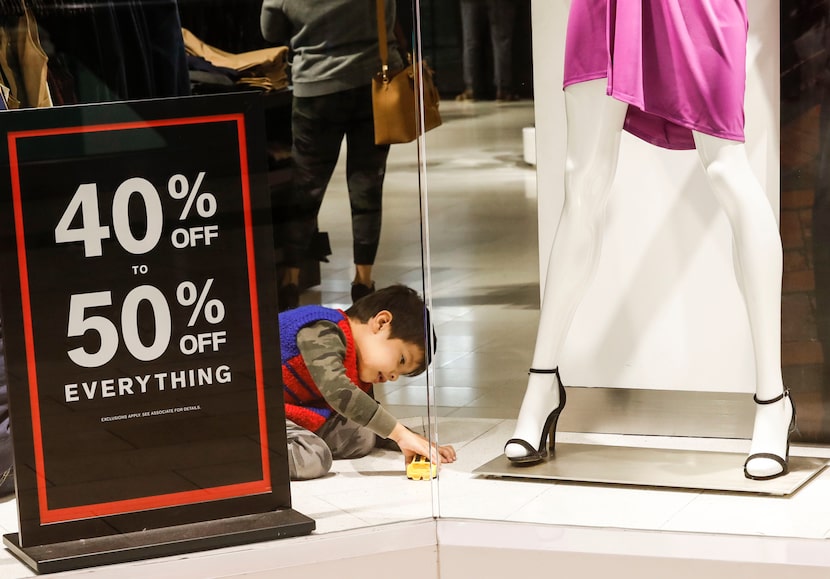 Jayden Vasquez, 5, plays with a yellow Transformers car in Express' store window during...