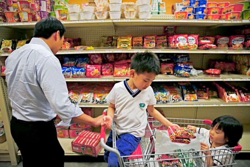 
Six-year-old Chester Sheu hands noodles to his 4-year-old sister, Alyssa Sheu, as they help...