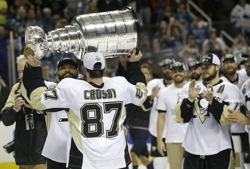 Pittsburgh Penguins center Sidney Crosby (87) hands the Stanley Cup to defenseman Trevor...