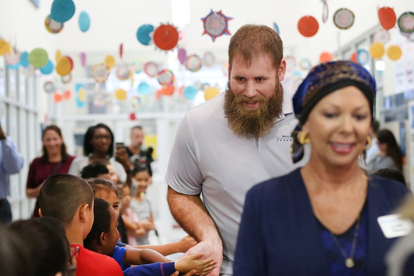 Dallas Cowboys center Travis Frederick high five a line of first graders as part of...