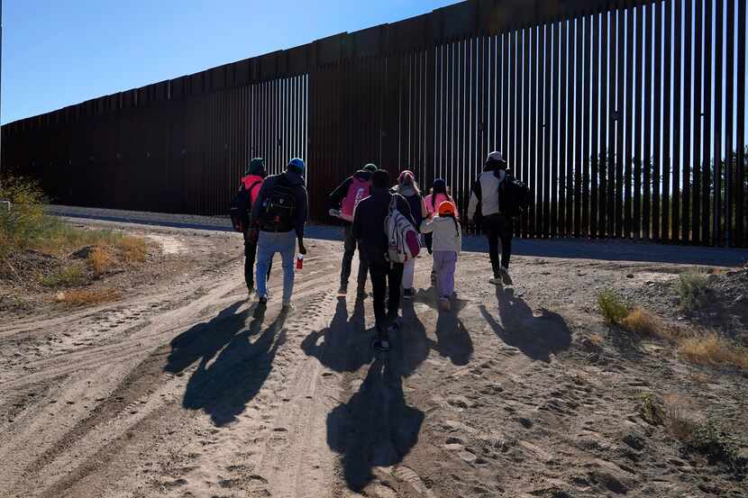 Un grupo de migrantes caminan junto a la frontera en una parte remota del desierto de...