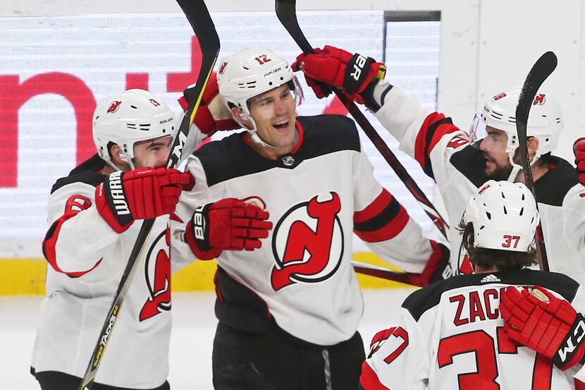 New Jersey Devils' Ben Lovejoy, second from left, is greeted by teammates after he scored...