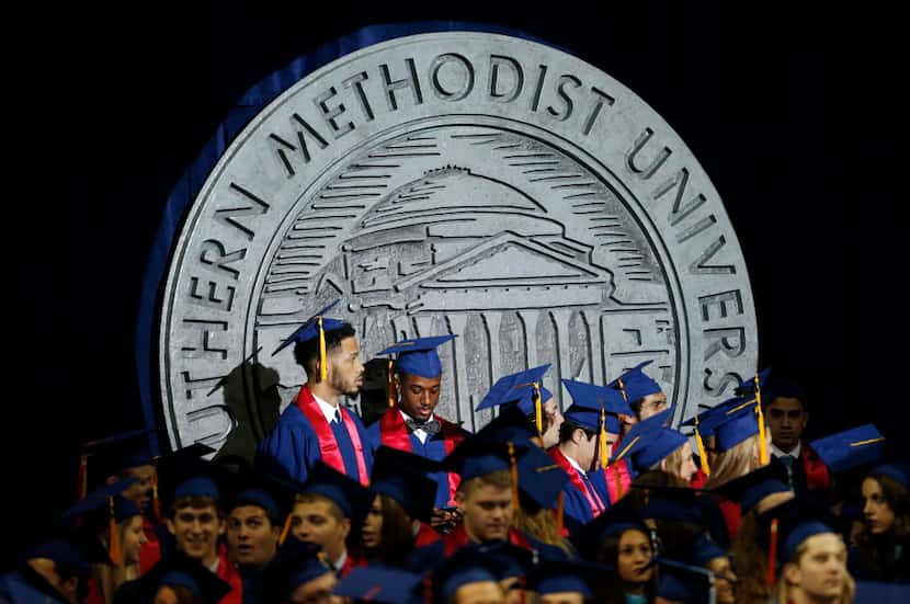 Students stand in front of a large placard during the SMU May Commencement Convocation...