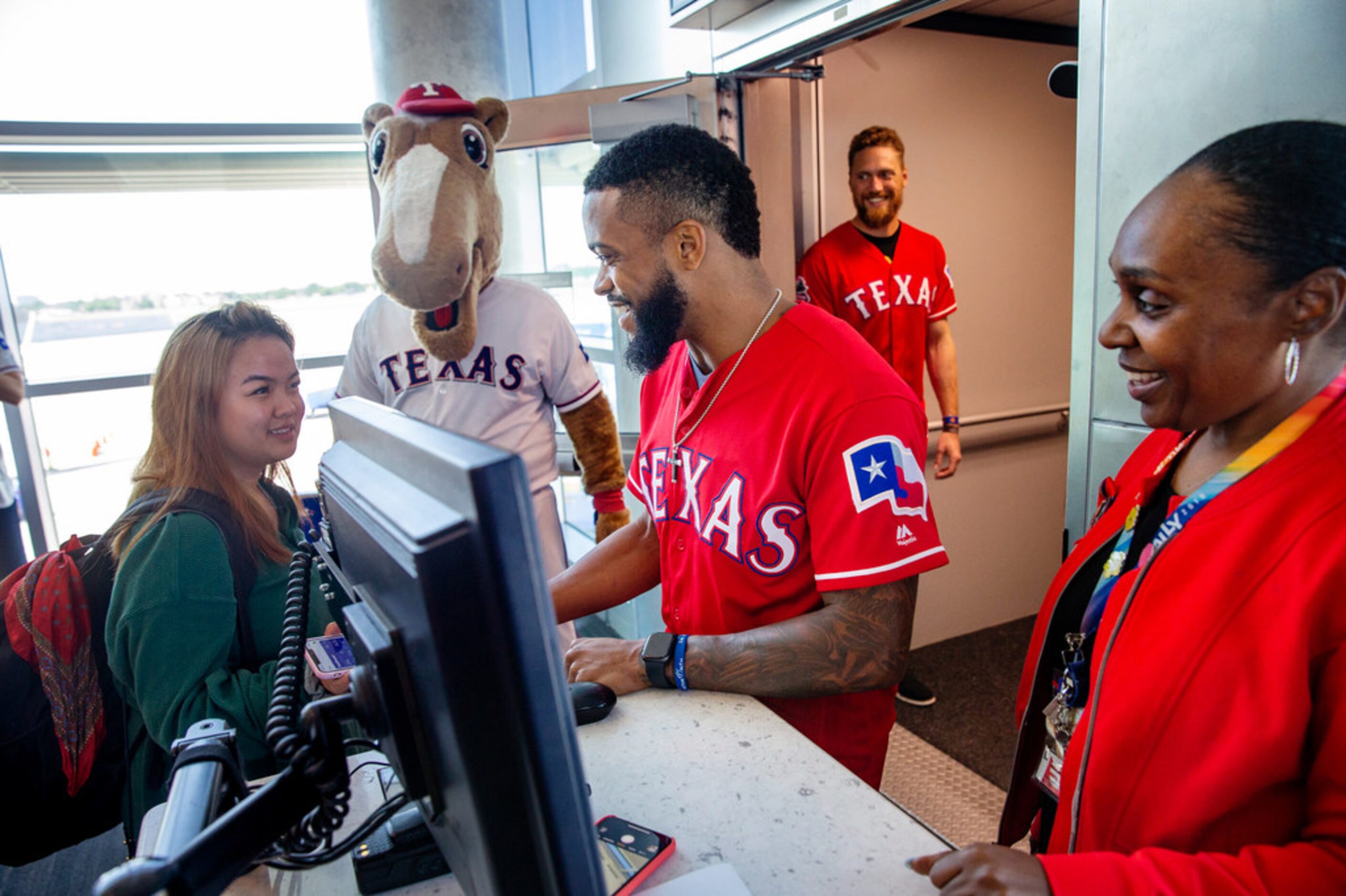 Texas Rangers player Delino DeShields Jr. (center) accepts boarding passes with the guidance...