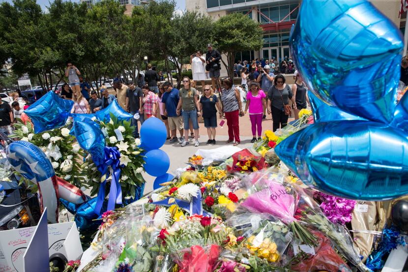 People form a prayer circle surrounding  the memorial for the slain officers at the Dallas...