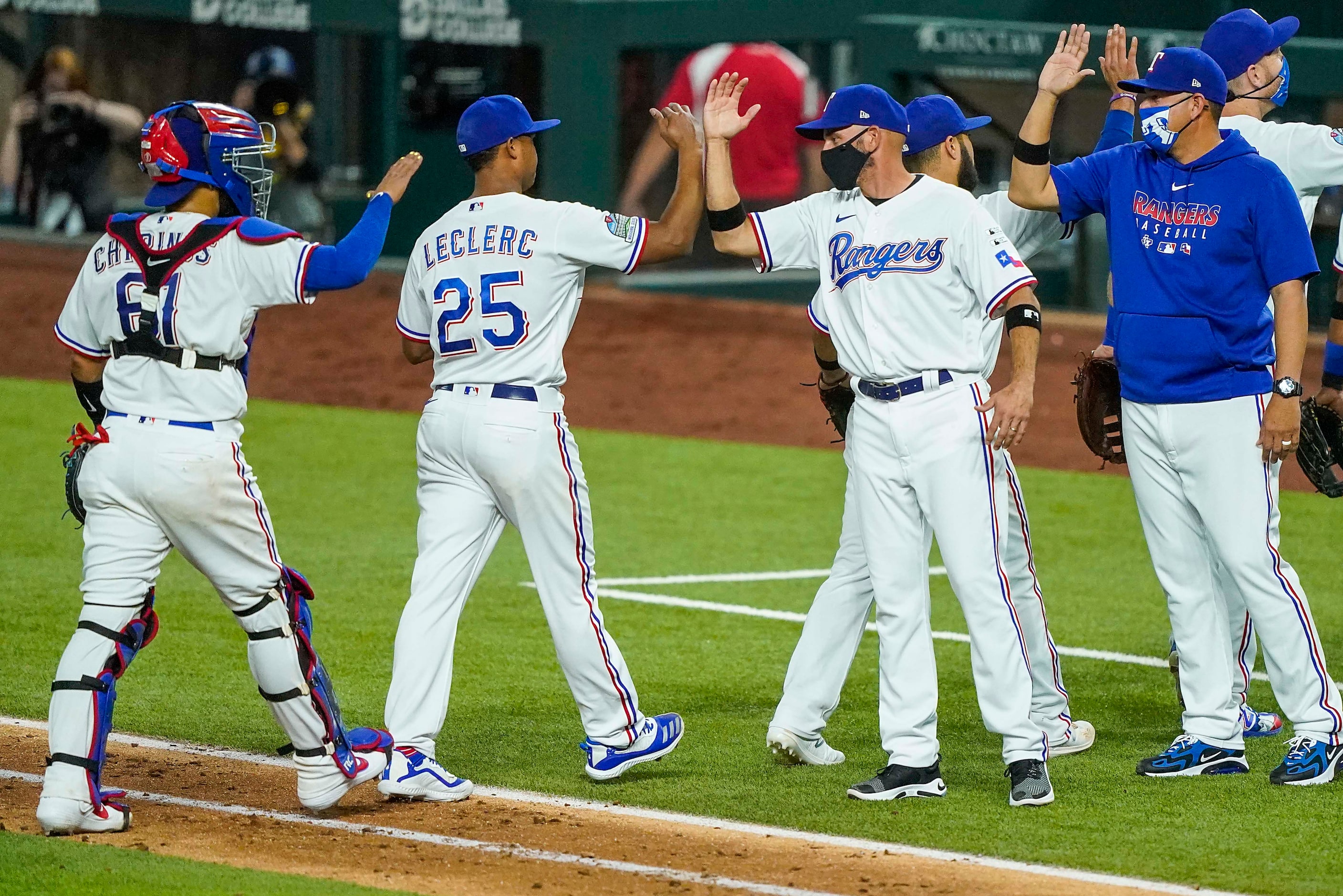 Texas Rangers pitcher Jose Leclerc bumps forearms with manager Chris Woodward as they...