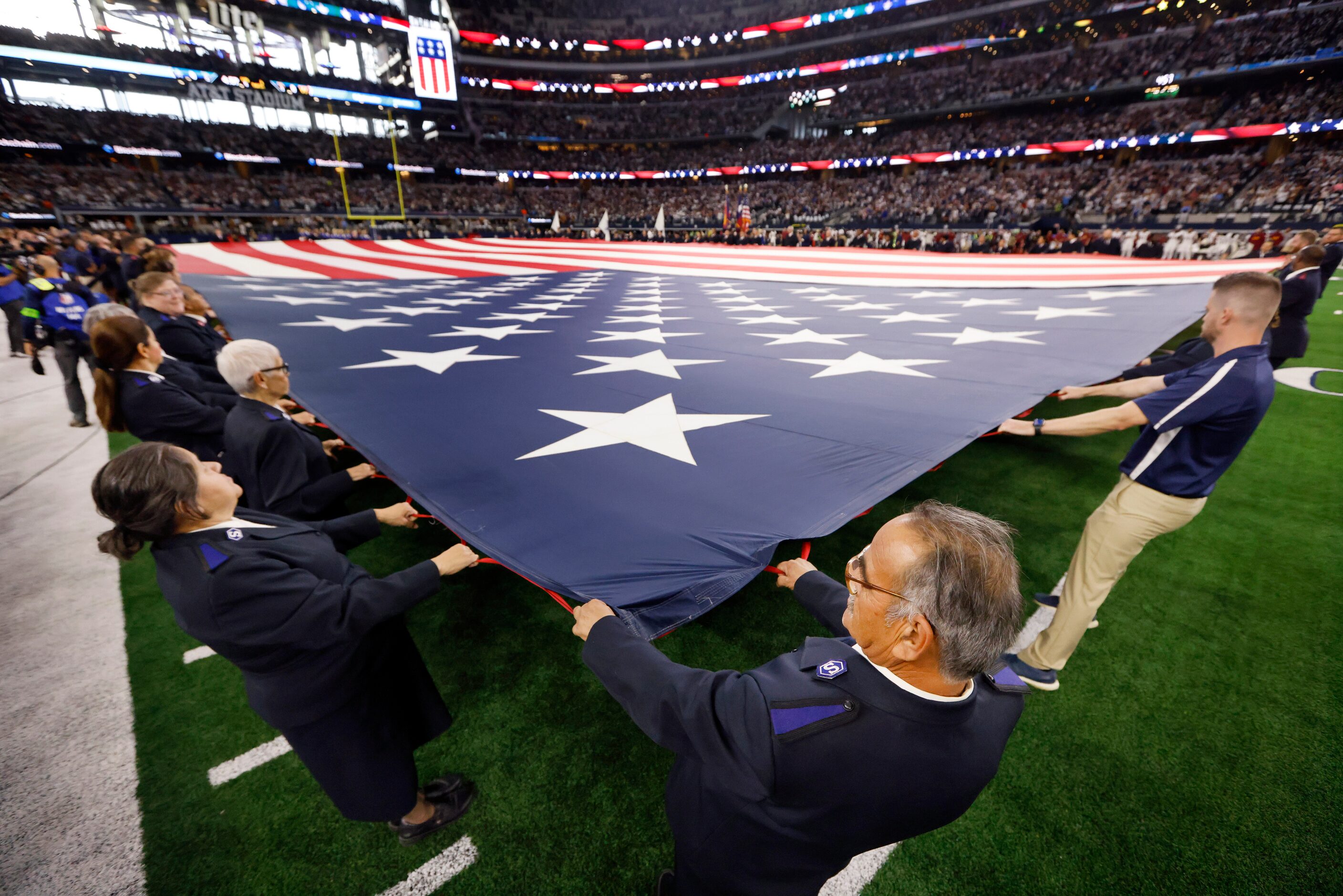 Members of the Salvation Army stretch the U.S. flag across the field during the national...