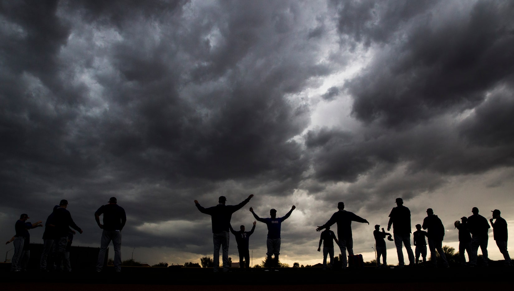 Texas Rangers warm up under rain clouds during a spring training workout at the team's...