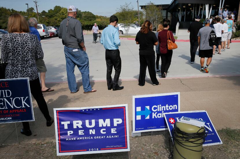 Early voters stand by campaign signage as they wait in line at a voting location, Thursday,...