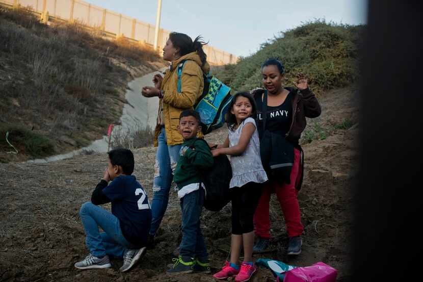 In a photo taken from the Tijuana, Mexico, side of the border, Honduran migrants react as...