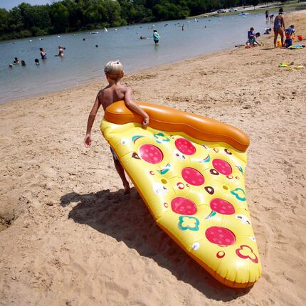 Camden Clark, 10, of Frisco drags his inflatable slice of pizza across Little Elm Park beach...