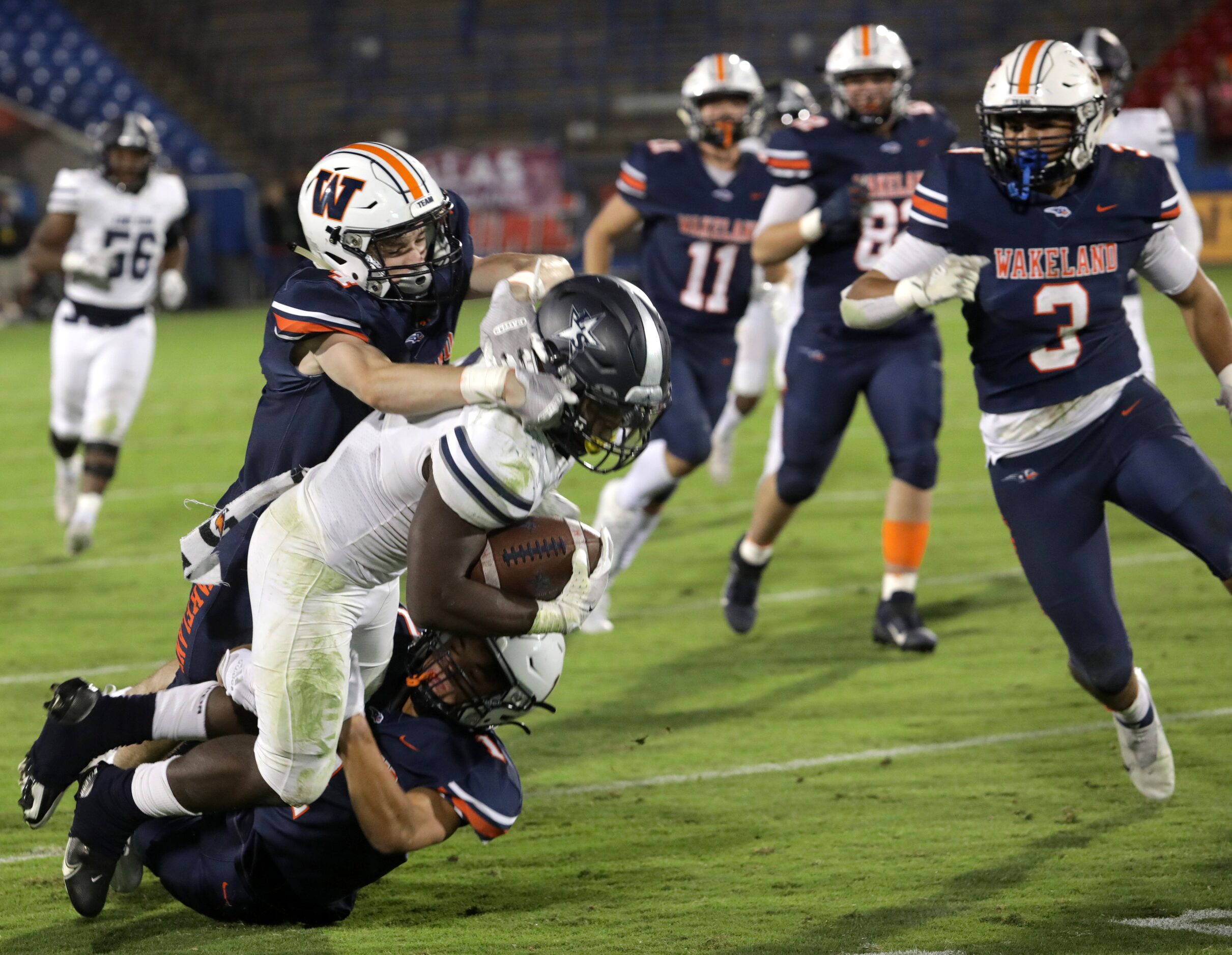 Lone Star player #2, Ashton Jeanty, is tackled by Wakeland players #4, Gus England, and #1,...