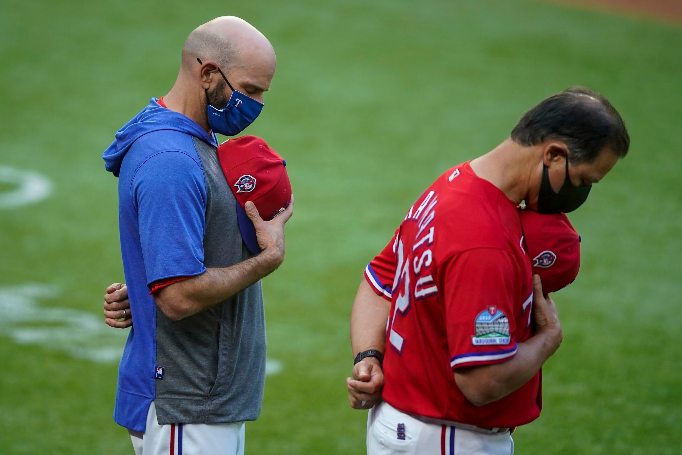 Texas Rangers manager Chris Woodward and bench coach Don Wakamatsu bow their heads during a...