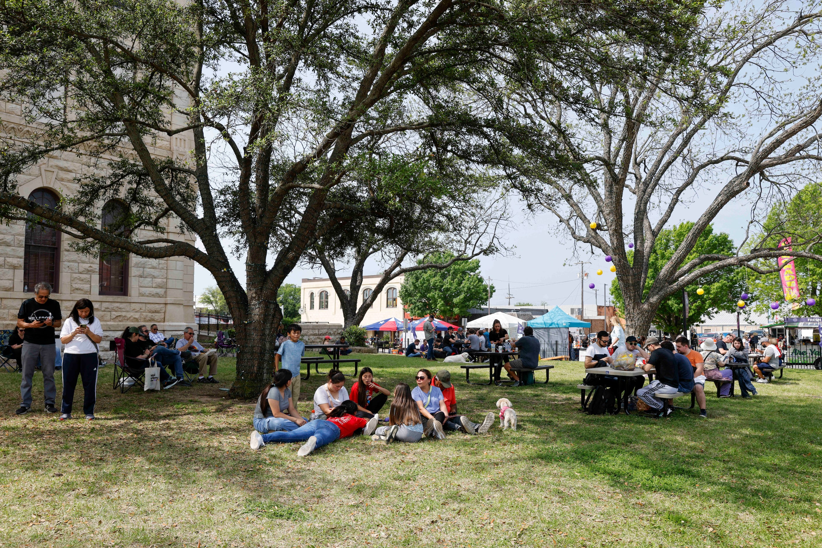 People sit and wait outside the Hill County Courthouse for a total solar eclipse, Monday,...