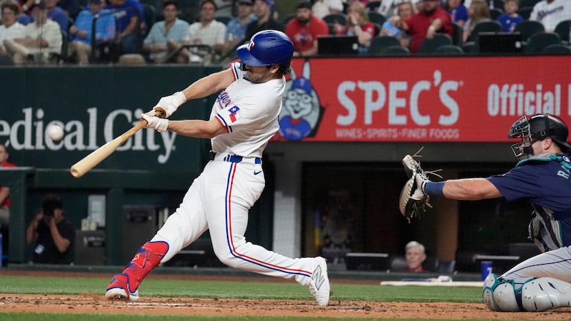 Texas Rangers' Josh Smith homers, left, in front of Seattle Mariners catcher Cal Raleigh...