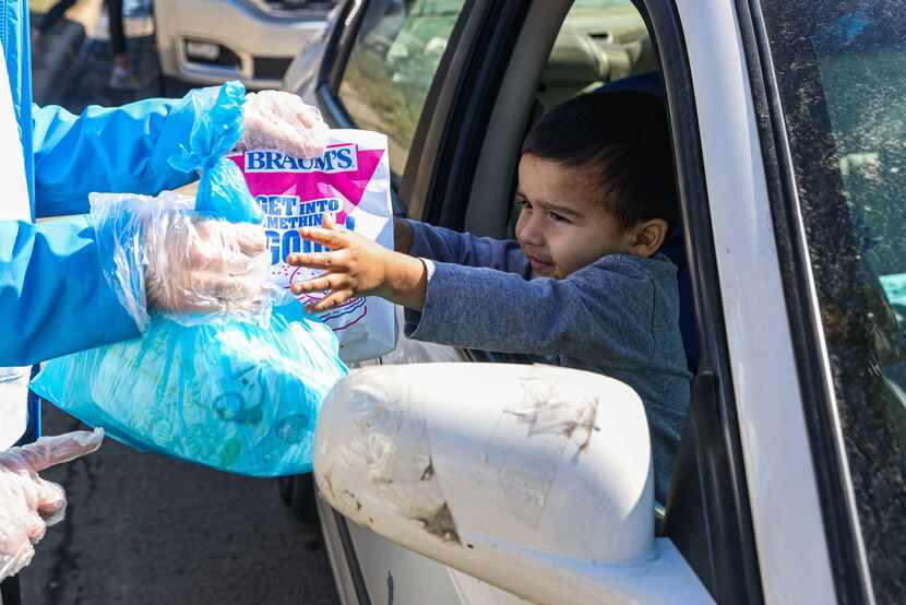 Adolfo Chavarria, 3, received food aid from volunteer Rachel Harper, 15, at the Ledbetter...