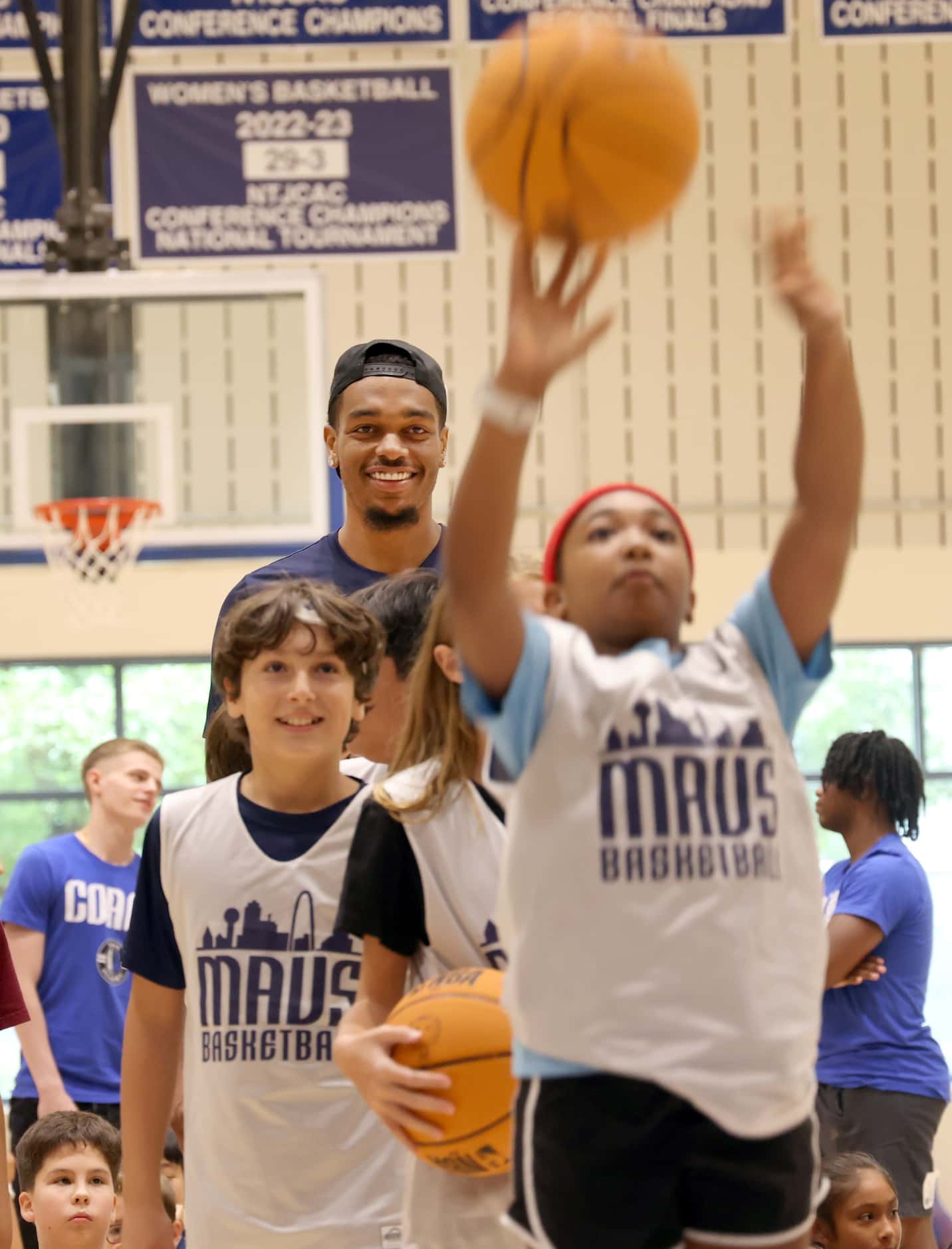 Dallas Mavericks forward and center PJ Washington, background, oversees campers during a...