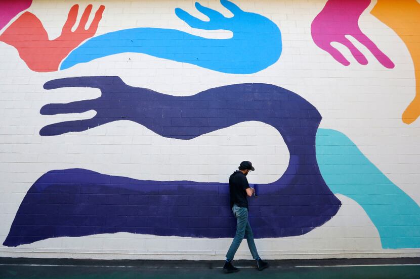 Kyle Steed works on his mural at the Plaza of the Americas building in downtown Dallas....