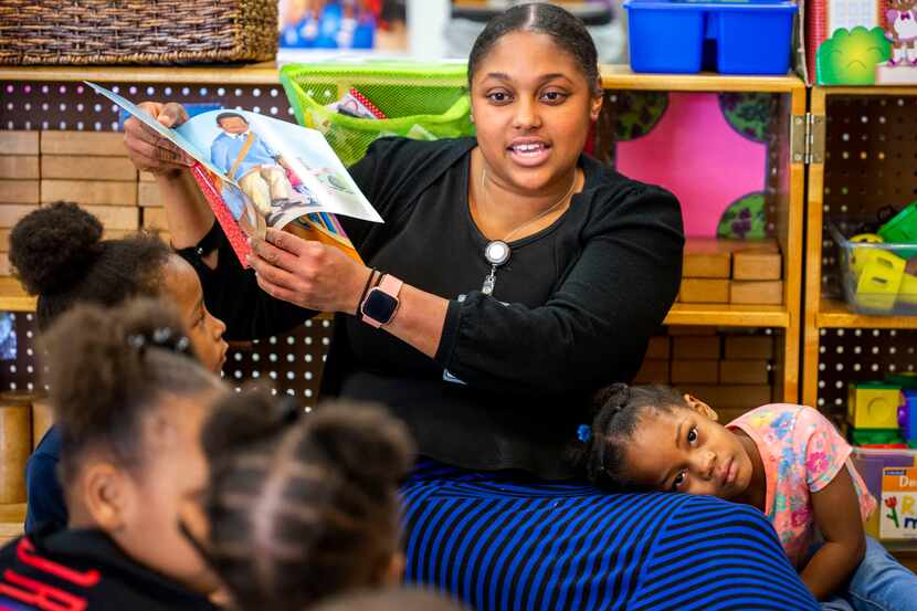 Erika Littlejohn, 3, leans on Natasha Hymes as she reads a book to the class at...