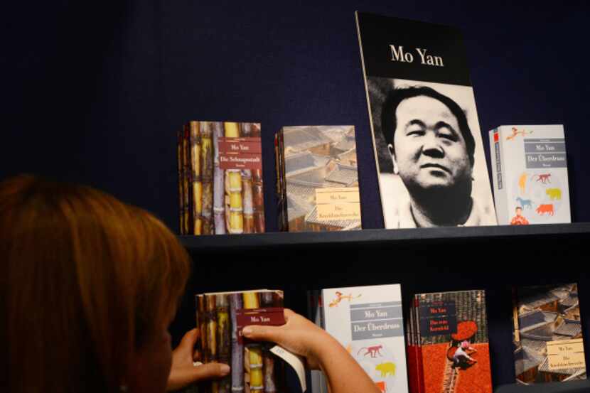 A woman places a poster of Chinese author Mo Yan, the 2012 Nobel Literature Prize winner, at...