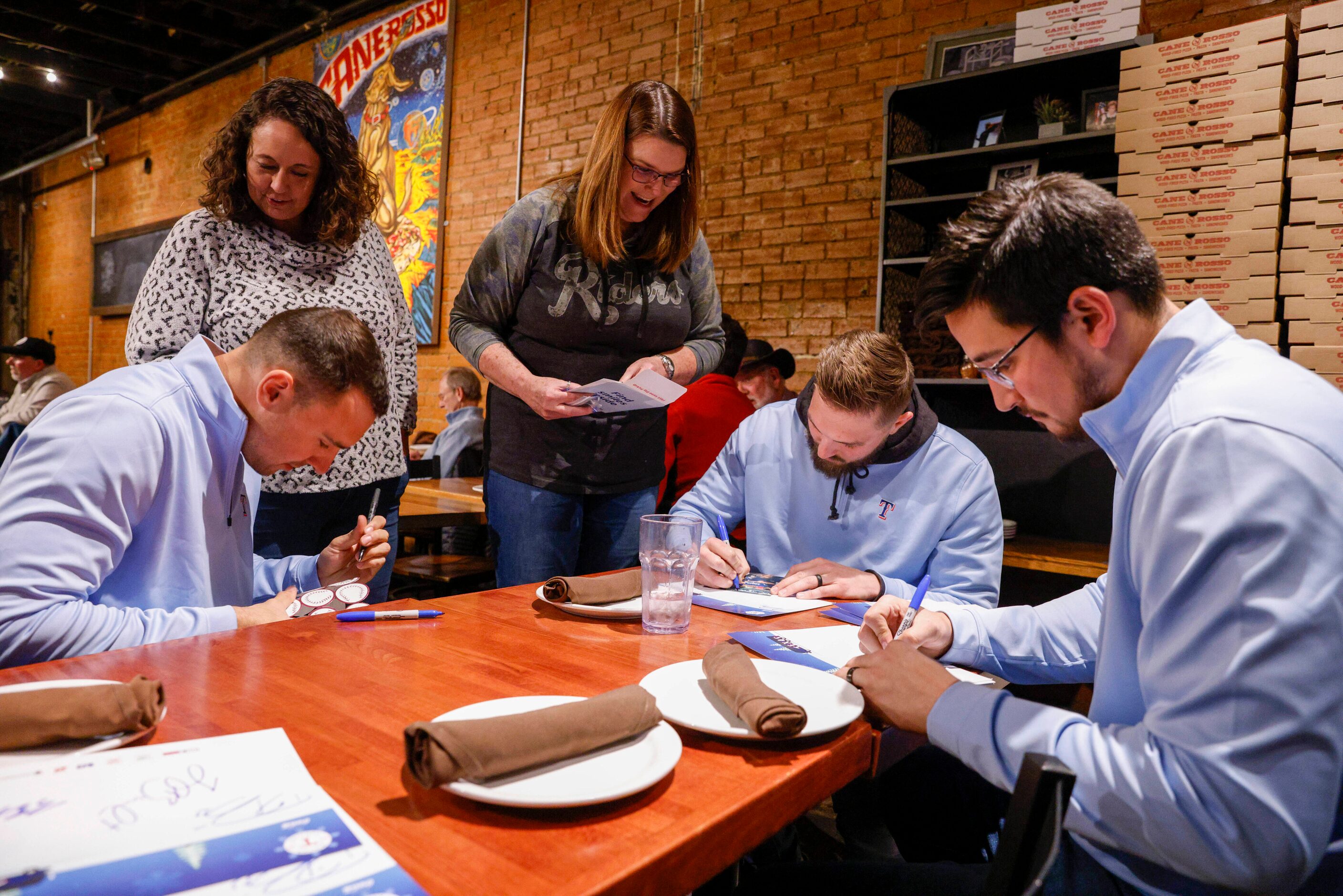 Texas Rangers pitchers Brock Burke (left), Joe Barlow (center) and Dane Dunning sign...