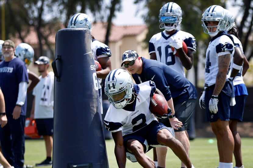 Dallas Cowboys wide receiver KaVontae Turpin digs around a blocking dummy as he carries the...